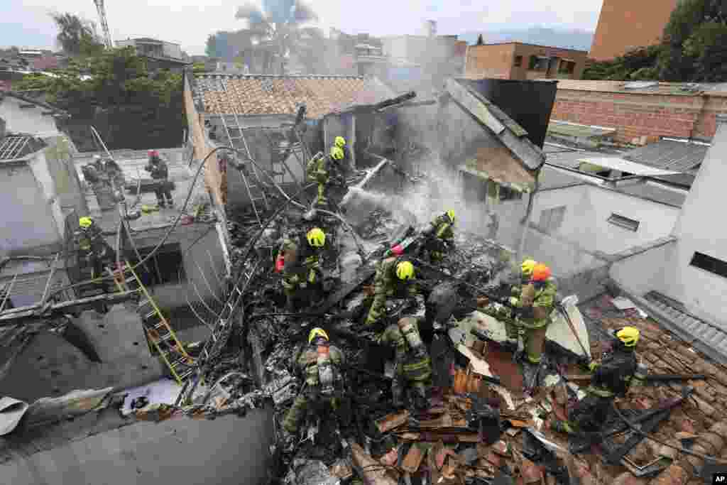 Firefighters work at the crash site of a small plane that fell on top of homes in a residential area of Medellin, Colombia. The plane crashed shortly after taking off from Medellin's Olaya Herrera airport, killing at least eight people including two members of the crew and his six passengers, according to city Mayor Medellin Daniel Quintero.
