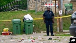 Seorang petugas polisi berdiri di area insiden penembakan massal di Distrik Selatan Baltimore, 2 Juli 2023.