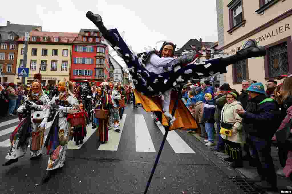 A carnival reveler performs the so-called "Fools Jump" during the traditional folklore procession "Narrensprung" in the Black Forest town of Rottweil in south-western Germany.