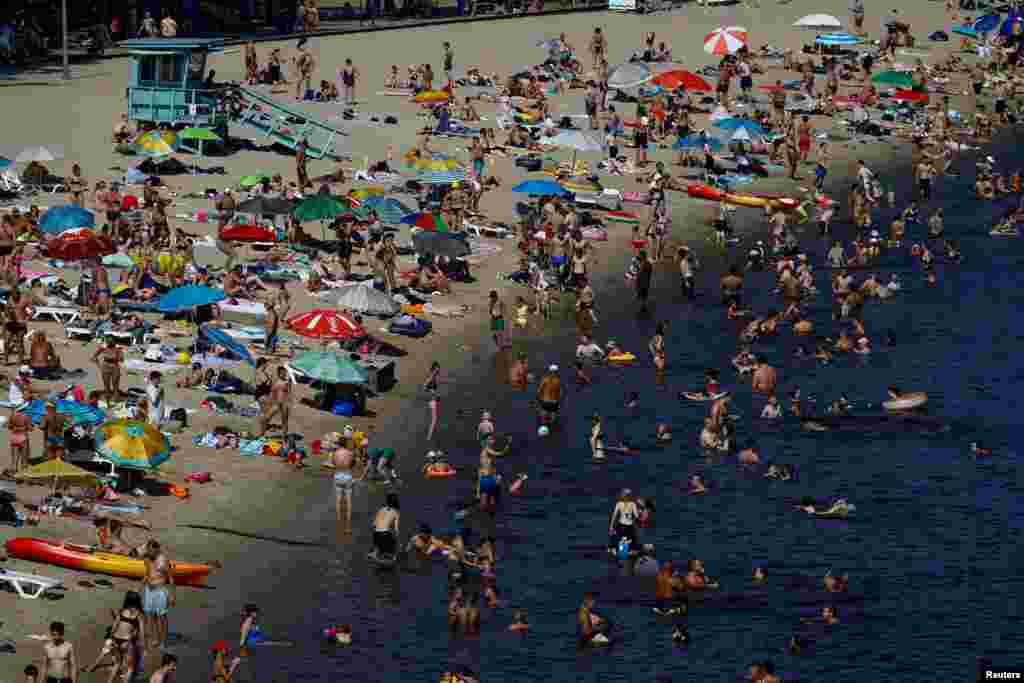 People rest at a city beach on the bank of the Dnipro River on an extremely hot summer day, amid Russia's attack on Ukraine, in Kyiv, Ukraine.