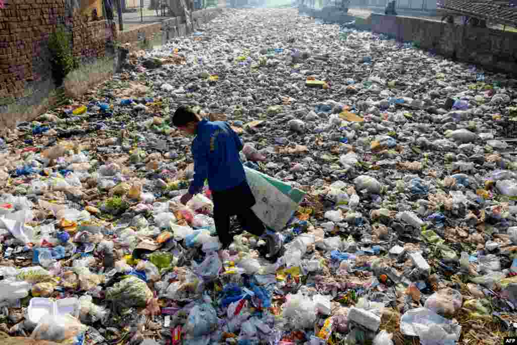 A waste picker scouts for recyclable junk from a sewage drain used as a garbage dump at a slum area in Lahore, Pakistan.