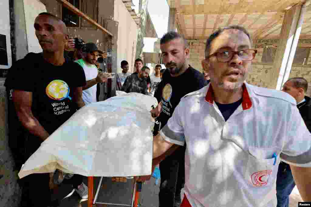 People carry the body of one of the foreign workers from the World Central Kitchen (WCK), who were killed in an Israeli airstrike, before they are transported to their families, in Rafah, in the southern Gaza Strip.