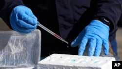 Un oficial antinarcóticos realiza un análisis químico para confirmar la pureza de un bloque de cocaína, en Cayambe, Ecuador, el viernes 3 de marzo de 2023.