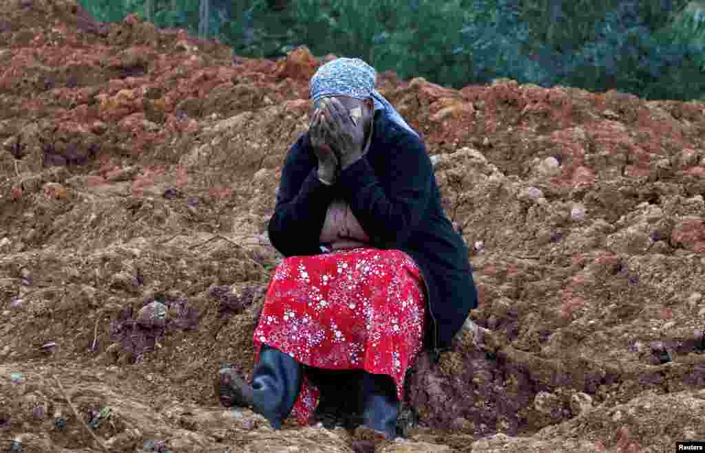 Esther Kinyanjui reacts as she sits near the search and rescue operations for people who are feared trapped at the scene of a landslide following heavy rains in Matathia area of Kimende Escarpment, in Kiambu County, Kenya.