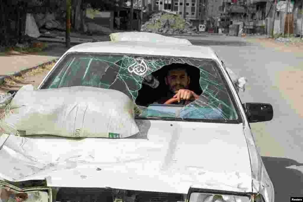 A displaced Palestinian man drives a car damaged during Israel's military offensive as he flees Rafah, after Israeli forces launched a ground and air operation in the eastern part of southern Gaza city.