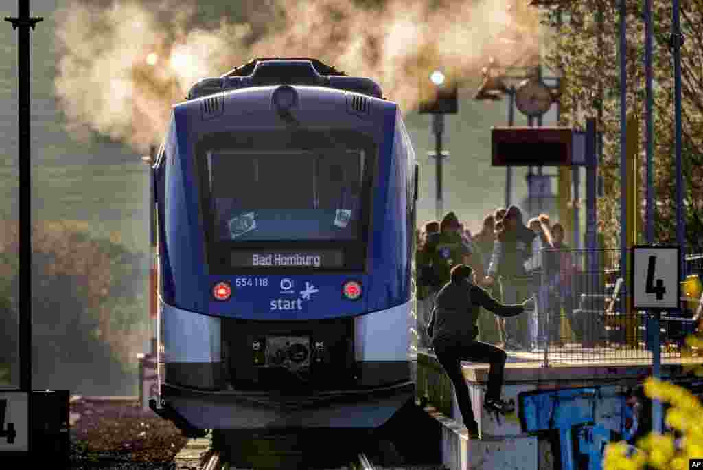 A man who has crossed the rails climbs onto the platform to catch a train at the small station of Wehrheim near Frankfurt, Germany.