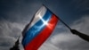 Seorang pria mengibarkan bendera nasional Rusia di pusat kota Moskow menjelang Hari Rusia pada 11 Juni 2023. (Foto: AFP/Kirill KUDRYAVTSEV)