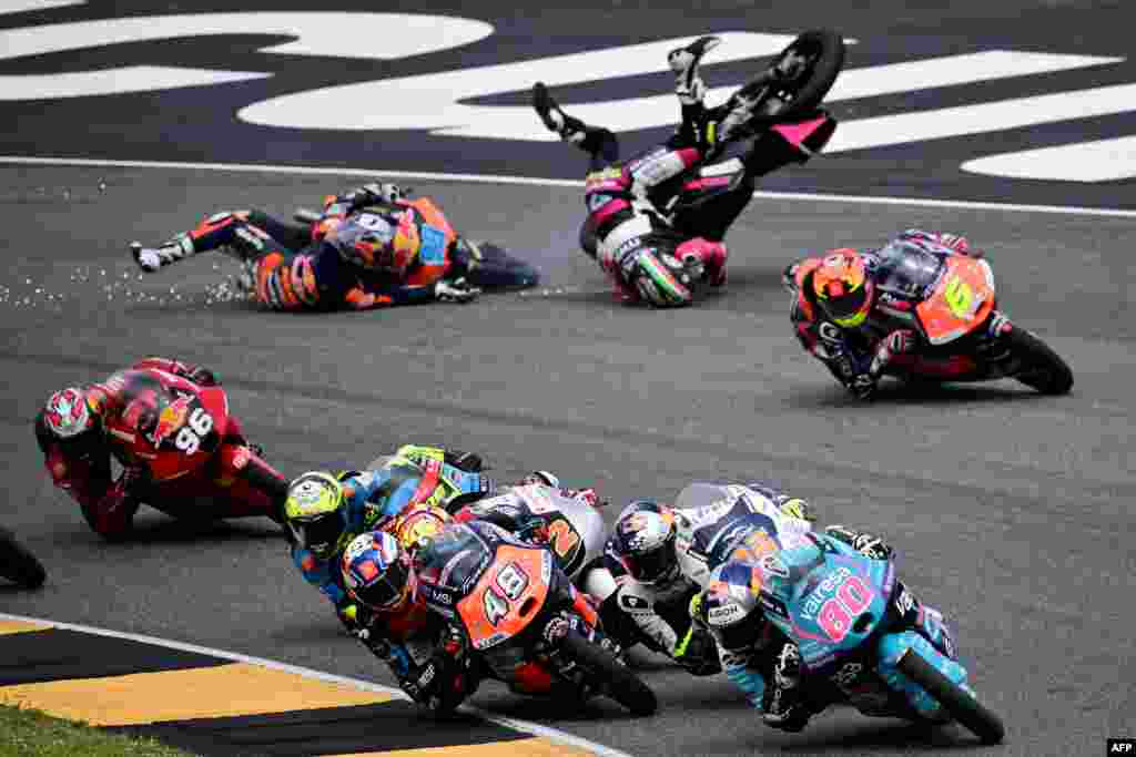 Spain's Red Bull KTM Ajo rider Jose Antonio Rueda (L) and Italy's MTA Team rider Stefano Nepa crash as Colombia's CFMOTO Aspar Team rider #80 David Alonso leads the pack during the Italian Moto 3 race at Mugello.