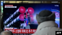Men watch a television showing a news broadcast with file footage of a North Korean military parade, at a railway station in Seoul, Feb. 20, 2023. 
