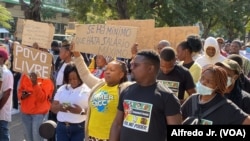 Manifestante exibe cartaz dizendo "Se há mínimo que haja salário máximo", durante marcha em Maputo pela democracia e melhores condições de vida. 24 junho 2023