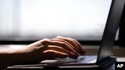 FILE - This May 18, 2021, photo shows a woman typing on a laptop in New Jersey.