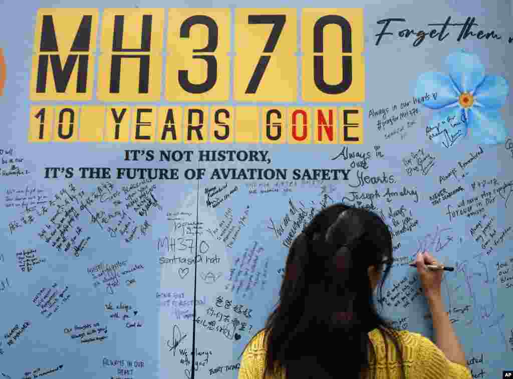 A woman writes a message on the message board during the tenth annual remembrance event at a shopping mall, in Subang Jaya, on the outskirts of Kuala Lumpur, Malaysia. Ten years ago, a Malaysia Airlines Flight 370, had disappeared March 8, 2014 while en route from Kuala Lumpur to Beijing with over 200 people on board. 