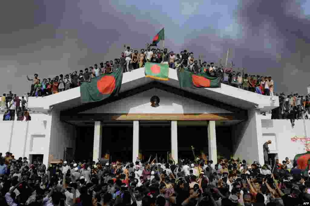 Anti-government protesters display Bangladesh's national flag as they storm Prime Minister Sheikh Hasina's palace in Dhaka, Aug. 5, 2024.