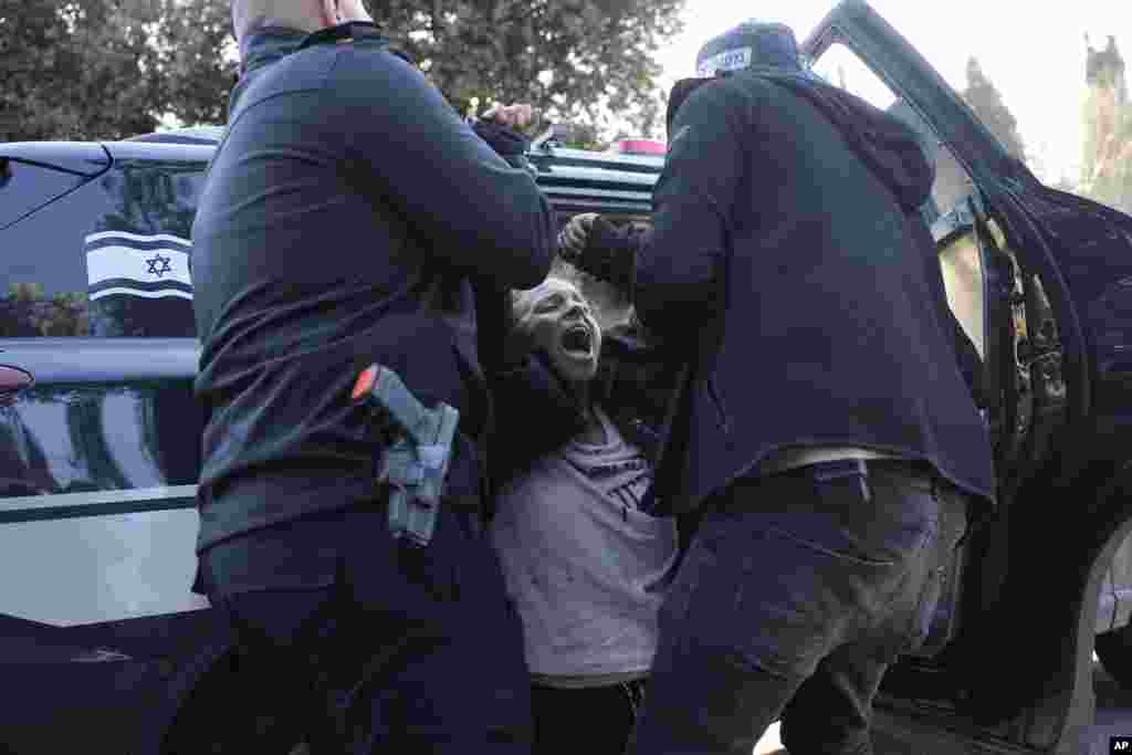 Police detain an anti-government protester who blocked an entrance to the Knesset, Israel's parliament in Jerusalem.