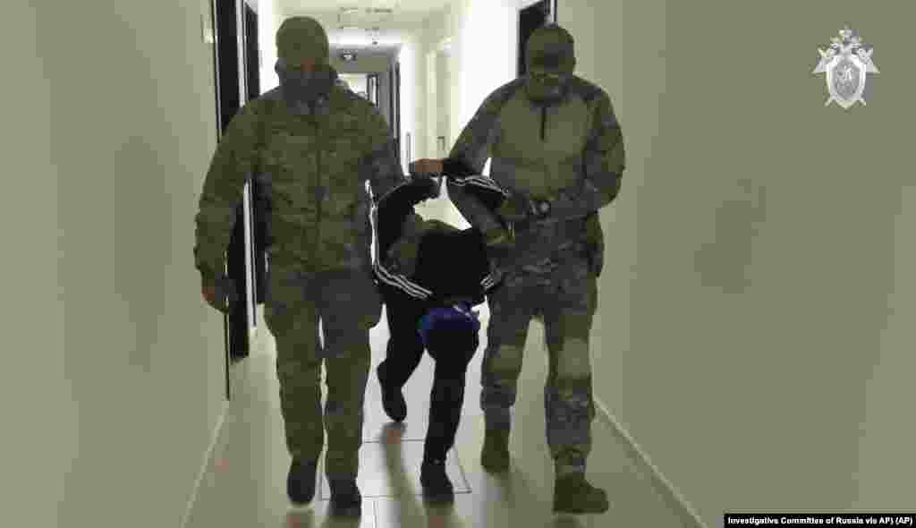 In this photo taken from video released by Investigative Committee of Russia on March 24, 2024, a suspect in the Crocus City Hall shooting on Friday is escorted inside the Russian Investigative Committee headquarters in Moscow, Russia.