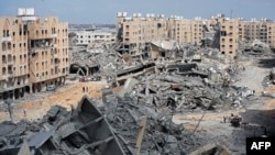 Pengungsi Palestina berjalan di tengah puing-puing rumah yang hancur akibat pemboman Israel di kawasan Hamad, sebelah barat Khan Yunis di Jalur Gaza selatan, 14 Maret 2024.
