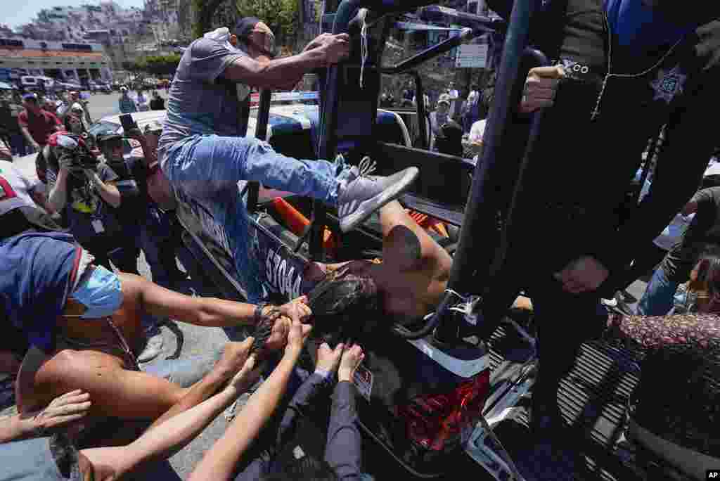 A woman suspected in the kidnapping and killing of an 8-year-old girl is dragged out of a police vehicle by a mob in Taxco, Mexico, March 28, 2024. Police then picked her up off the ground and took her away.