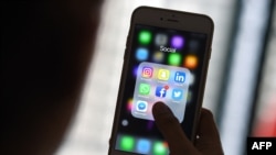 FILE - A woman looks at social networking apps Facebook, Instagram, Snapchat, Whatsapp, Twitter, Messenger and Linkedin on a smartphone in Kuala Lumpur, March 22, 2018.