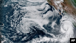 This Aug. 18, 2023, 1:10 p.m. EDT satellite image provided by the National Oceanic and Atmospheric Administration shows Hurricane Hilary, right, off Mexico’s Pacific coast.