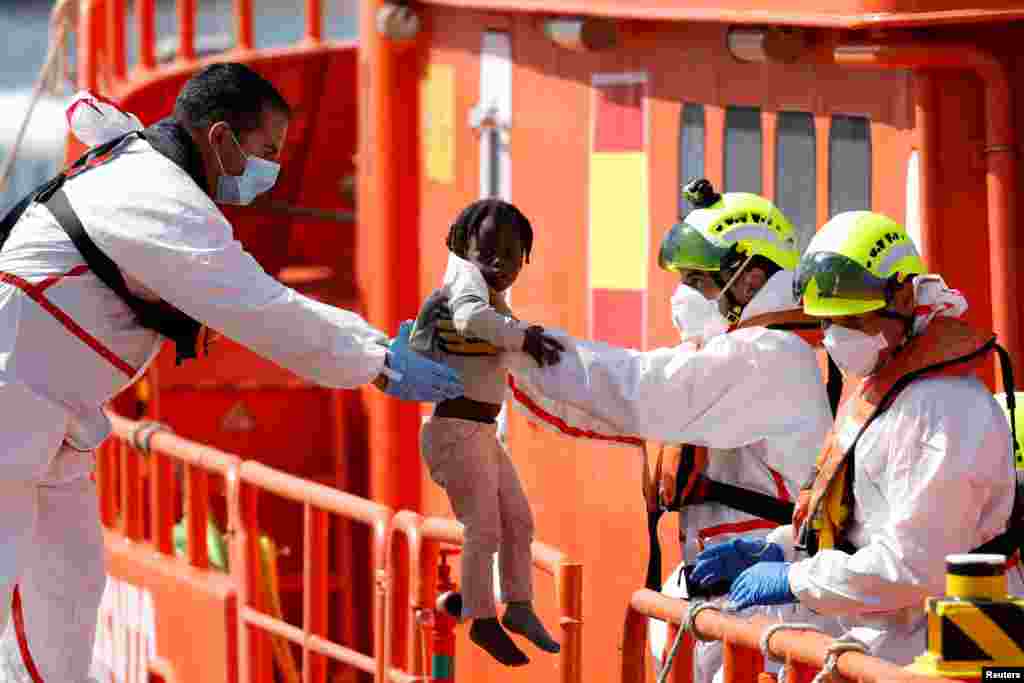 A rescuer helps a migrant child to disembark from a Spanish coast guard vessel at the port of Arguineguin on the island of Gran Canaria, Spain, May 20, 2024.