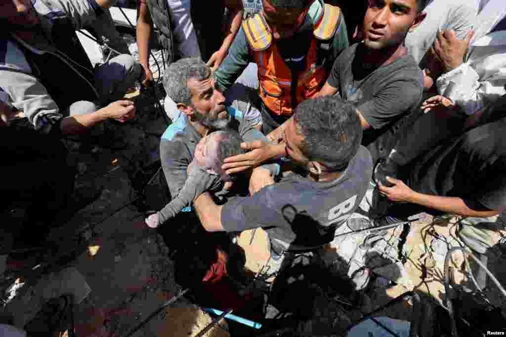 Palestinians carry the dead body of a child recovered from under the rubble of a house hit in an Israeli strike in Nuseirat refugee camp in the central Gaza Strip.