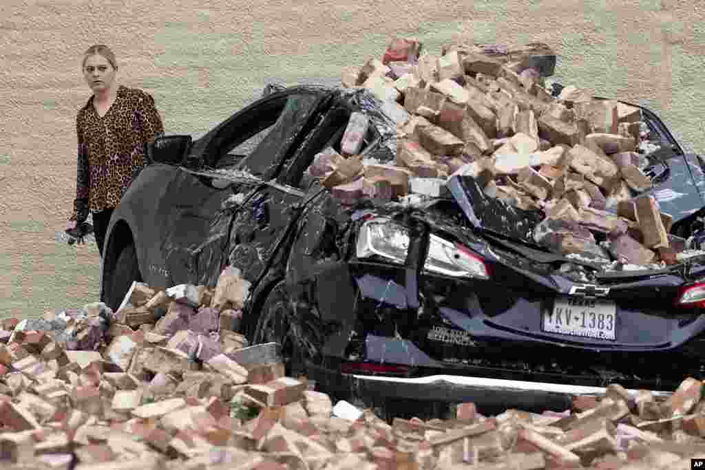A woman looks at the damage caused by fallen bricks from a building wall in the aftermath of a severe thunderstorm in Houston, Texas.