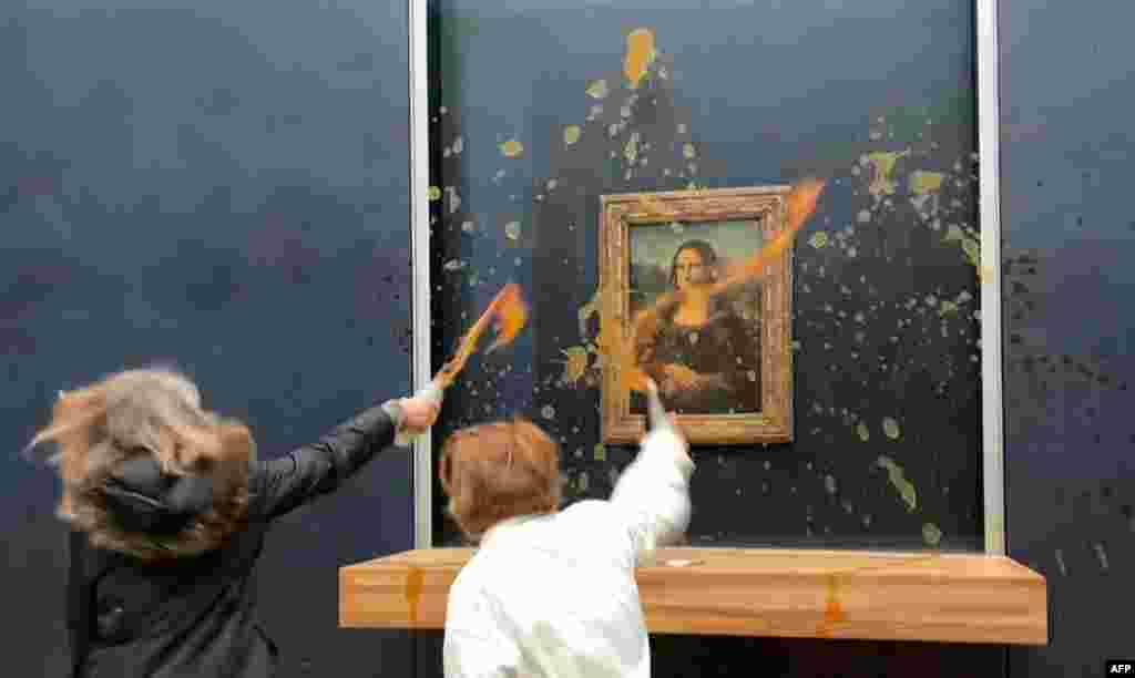 This image grab taken from AFPTV footage shows two environmental activists from the collective dubbed "Riposte Alimentaire" (Food Retaliation) hurling soup at Leonardo Da Vinci's "Mona Lisa" painting, at the Louvre museum in Paris.