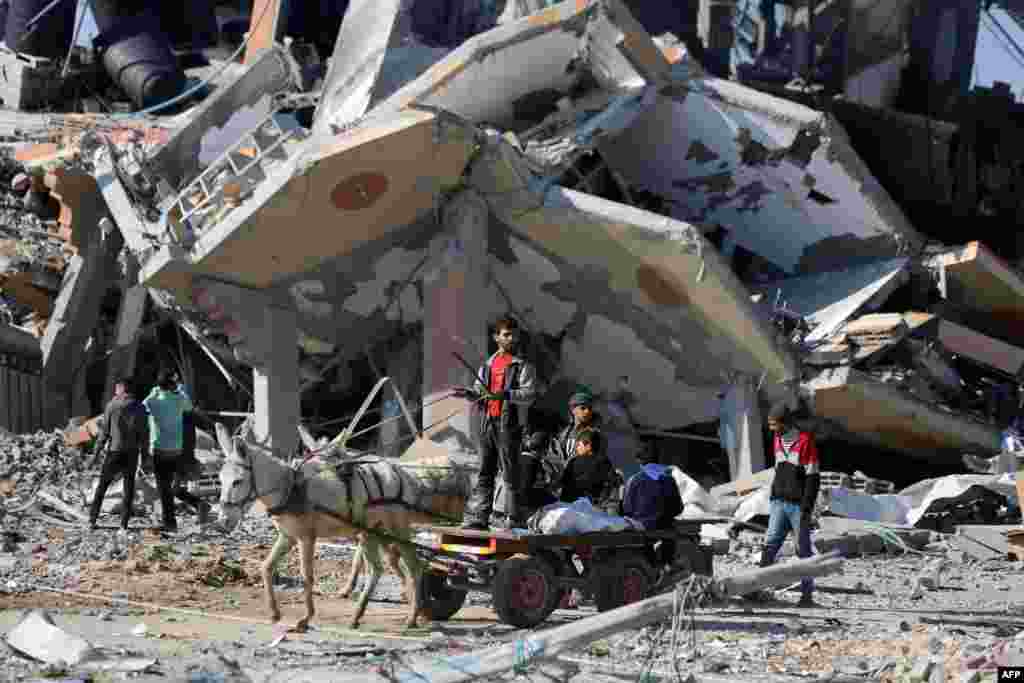 A donkey cart drives past a collapsed building in the Al-Maghazi refugee camp in central Gaza Strip.