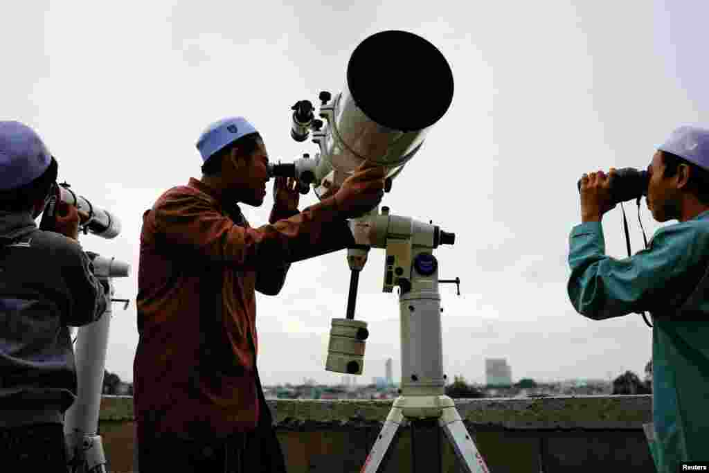 Muslim men look at the position of the moon to mark the first day of the holy fasting month of Ramadan, on the roof of Al-Musyari'in mosque in Jakarta, Indonesia.