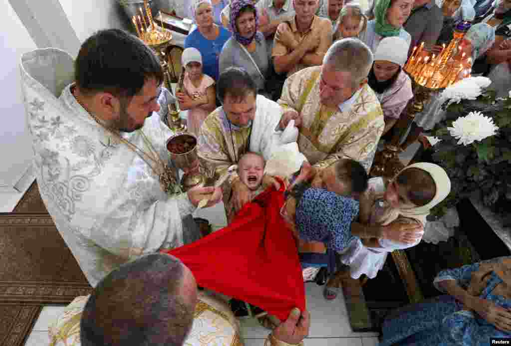 Worshippers take part in the ceremony of intinction during the celebration of the Apple Feast of the Saviour at a church in Yevpatoriya, Crimea.