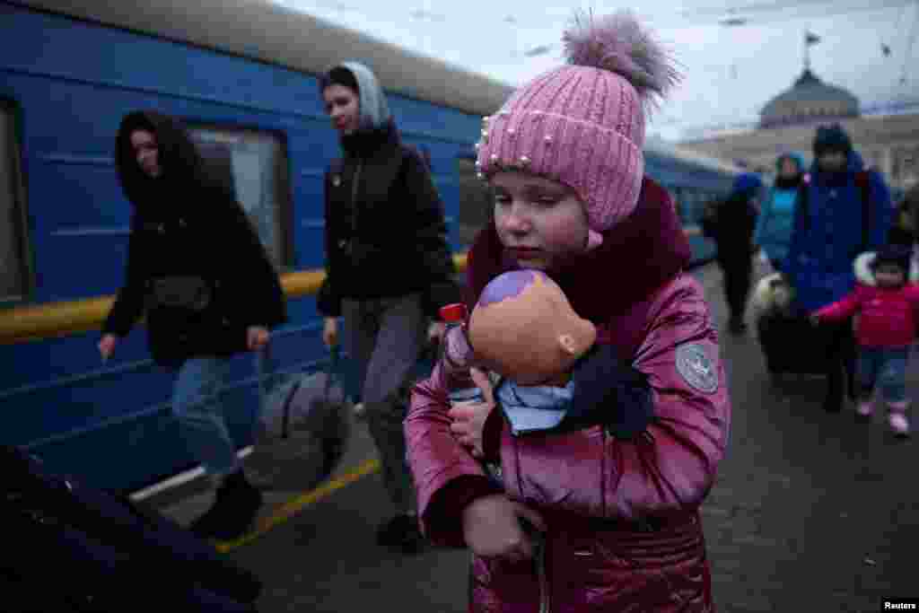 A girl holds a doll as civilians fleeing Russia's invasion of Ukraine board a train, in Odessa, March 8, 2022.