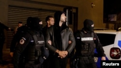 Andrew Tate dan Tristan Tate dikawal polisi di luar markas Direktorat Investigasi Kejahatan Terorganisir dan Terorisme di Bucharest (DIICOT) setelah ditahan selama 24 jam, di Bucharest, Rumania, 29 Desember 2022.