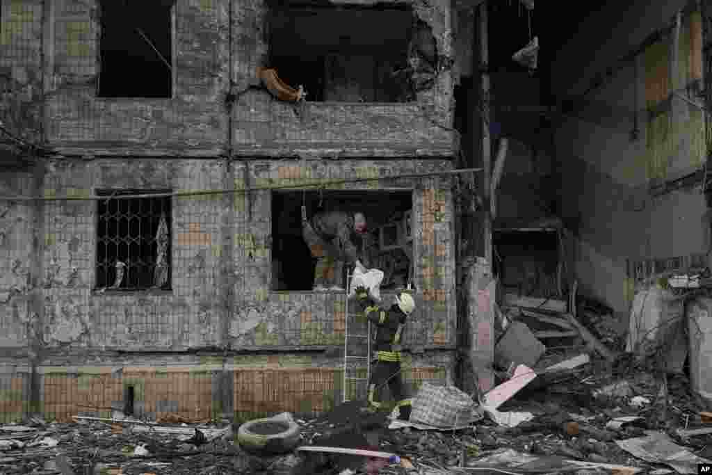People retrieve belongings from an apartment which was destroyed by an artillery strike in Kyiv, March 14, 2022. Russia's military forces kept up their punishing campaign to capture Ukraine's capital with fighting and artillery fire in Kyiv's suburbs after an airstrike on a military base near the Polish border brought the war dangerously close to NATO's doorstep.