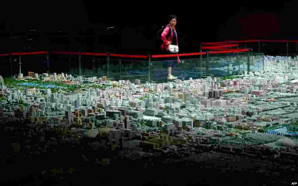 A woman looks at a scale model of Beijing's urban development at an exhibition center in Beijing, China.