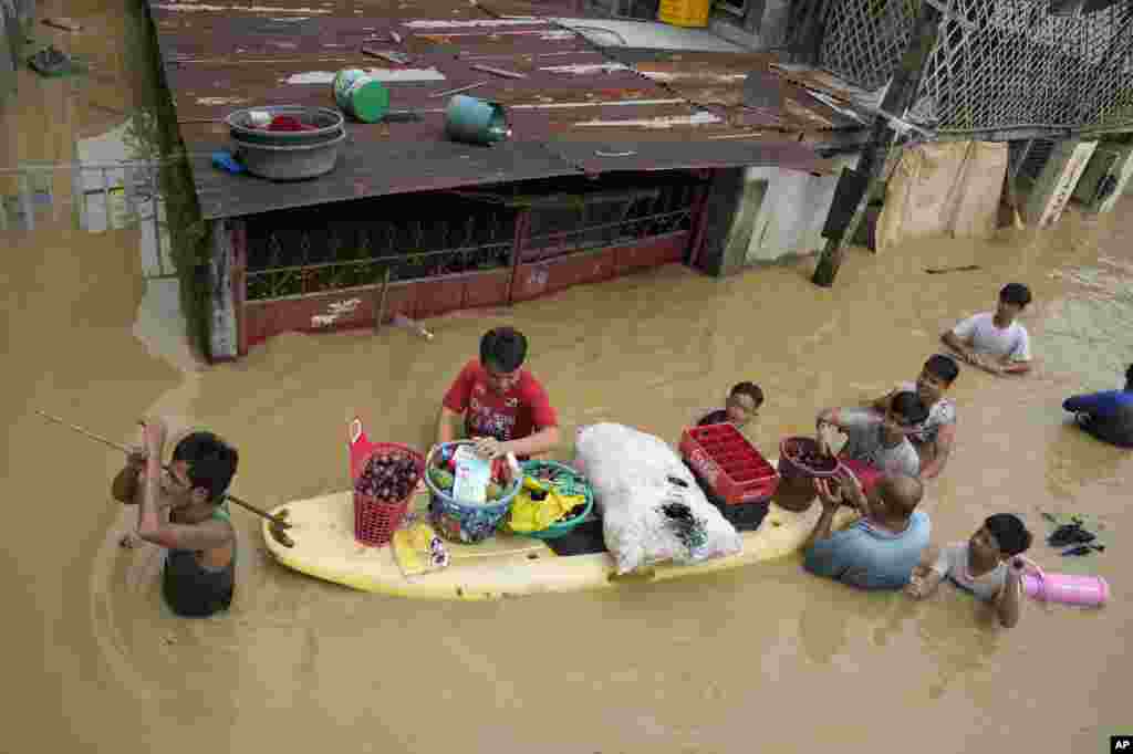 Residents give away onions and other foods along a flooded road due to Typhoon Noru in San Miguel town, Bulacan province, Philippines, Sept. 26, 2022.