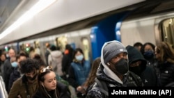 Sejumlah penumpang kereta di New York tetap mengenakan masker saat menggunakan sarana transportasi tersebut, pada 19 April 2022. (Foto: AP/John Minchillo)