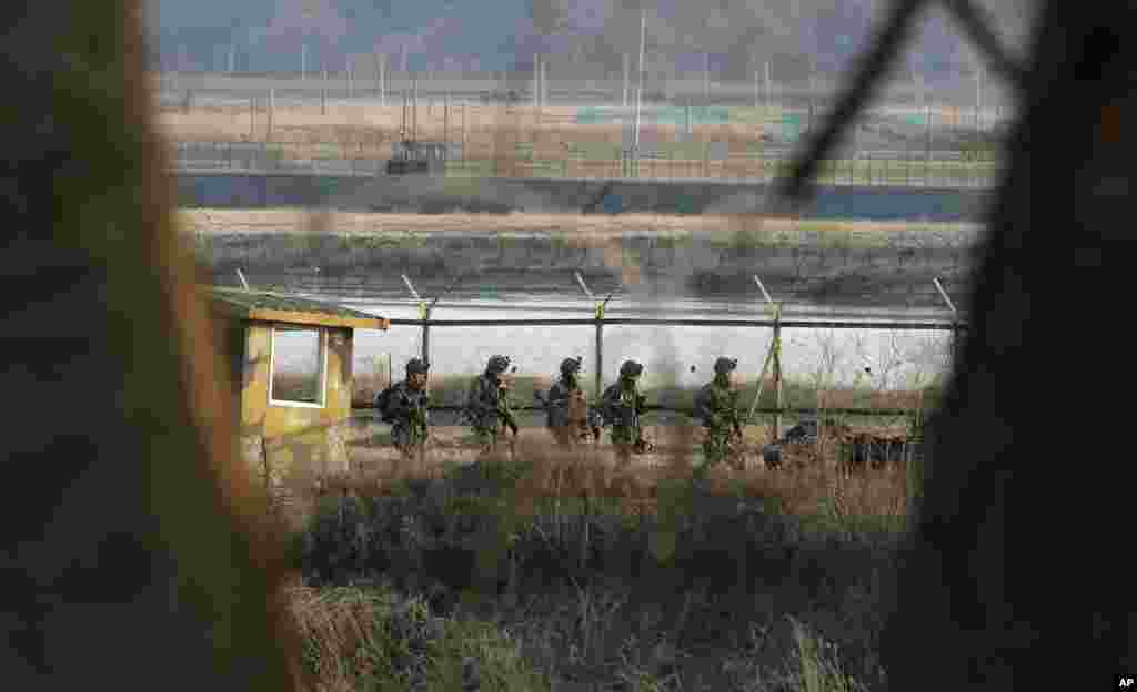 South Korean army soldiers patrol along a barbed-wire fence near the border village of Panmunjom in Paju, South Korea, March 27, 2013.