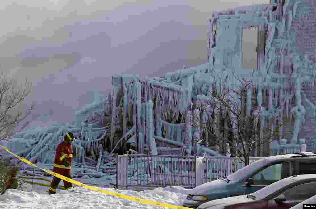 Petugas pemadam kebakaran melewati sebuah rumah jompo di kota L'Isle Verte, provinsi Quebec, yang terbakar habis pada saat musim dingin membeku sedang melanda Kanada.