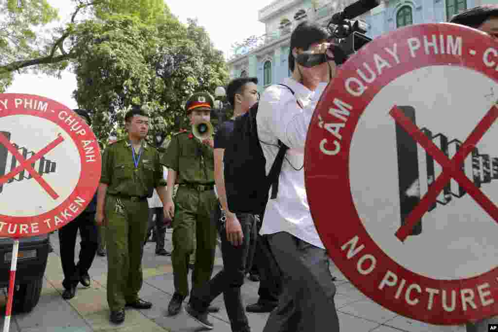 Seorang petugas polisi menggunakan pengeras suara untuk memerintahkan pejalan kaki, termasuk wartawan, untuk meninggalkan area yang tertutup dekat Kedutaan Besar China di Hanoi, Vietnam, 18 Mei 2014.