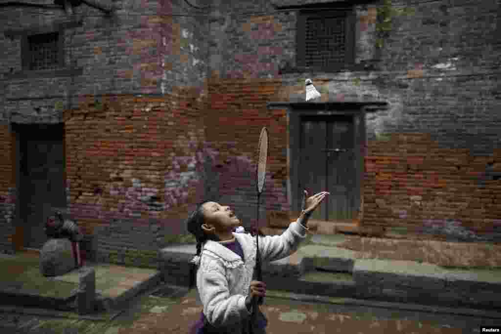 Seorang gadis bermain bulutangkis di sepanjang jalan di luar rumah-rumah tua kota kuno Bhaktapur, dekat ibukota Nepal, Kathmandu. 