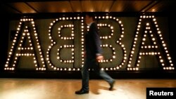 FILE - A man walks past the lit logo of the legendary Swedish pop group ABBA at "ABBA — The Museum" in Stockholm, May 6, 2013. 