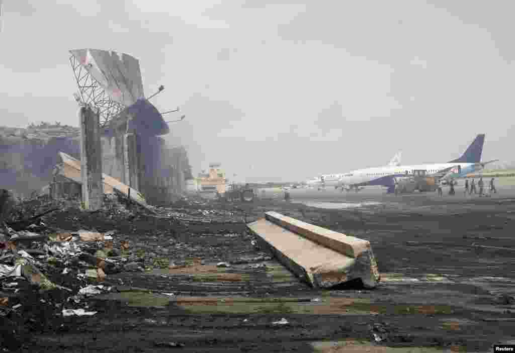 Planes are seen near a section of a damaged building at Jinnah International Airport, after Sunday's attack by Taliban militants, Karachi, Pakistan, June 10, 2014.