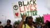FILE - Desiree Griffiths holds up a sign saying "Black Lives Matter", with the names of Michael Brown and Eric Garner, two black men recently killed by police, during a protest, in Miami, Florida, Dec. 5, 2014. 