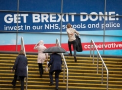 Delegates arrive in heavy rain at the Conservative Party Conference in Manchester, England, Oct. 1, 2019.