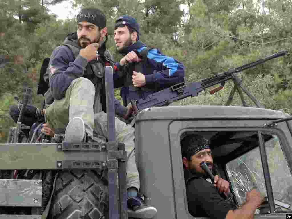 This citizen journalism image provided by Edlib News Network shows Free Syrian Army fighters on top of a military truck that was captured from the Syrian Army, Khirbet al-Jouz, Idlib, Syria, October 7, 2012.