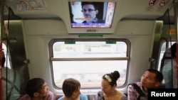 Los pasajeros del tren en Hong Kong escuchan noticias de que Snowden dijo al periodista Greenwald del diario The Guardia que no facilitó información a China ni a Rusia.