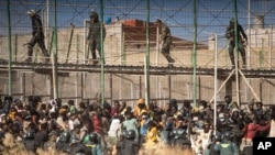 Polícia de choque isola a área depois da chegada migrantes a solo espanhol depois de cruzar as cercas que separam o enclave espanhol de Melilla de Marrocos em Melilla, Espanha, em 24 de Junho de 2022.