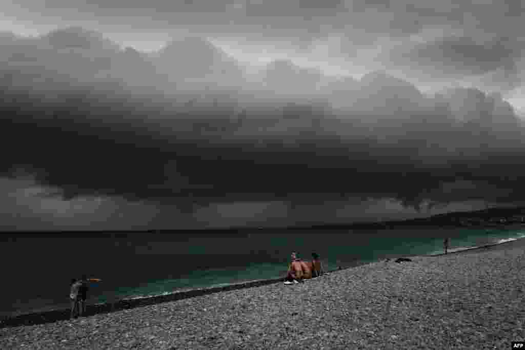 Beach-goers look at the clouds before a storm along the "Promenade des anglais" on the French Riviera city of Nice, June 28, 2022.