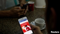 FILE PHOTO: A cellphone user looks at a Facebook page at a shop in Latha street, Yangon, Myanmar August 8, 2018. REUTERS/Ann Wang/File Photo