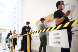 People queue to receive a dose of the Pfizer BioNTech vaccine at the Central Middlesex Hospital in London, Britain, August 1, 2021.